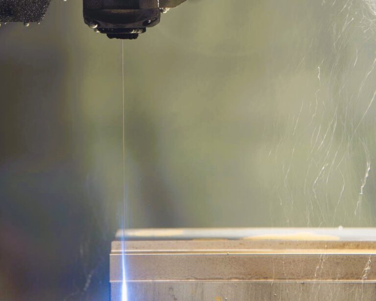 Fil d’électroérosion en action découpant un bloc métallique sur une machine d’usinage de précision.